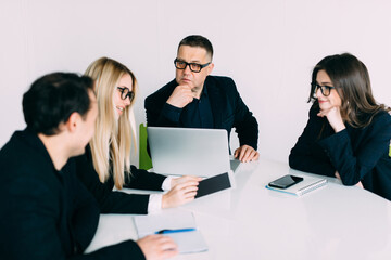 Business people showing team work while working in board room in office interior. People helping one of their colleague to finish new business plan. Business concept. Team work.