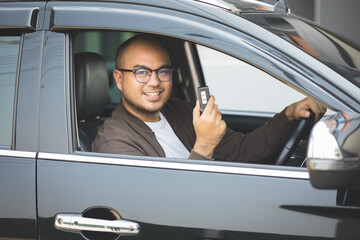 Young asian men around 30 getting new car. He very happy and excited. He showing car key to camera.