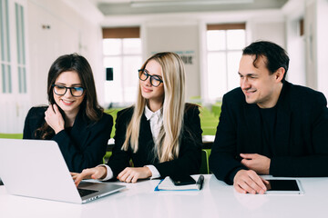 Startup business team brainstorming and working on laptop and computer. Three people working together in office over new business project.