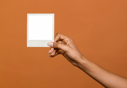Black female hand holding up a blank instant photo frame