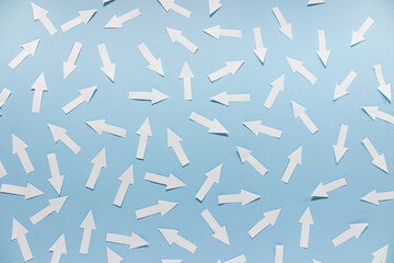 Concept of chaos randomly arranged many white paper arrows on blue background. - obrazy, fototapety, plakaty