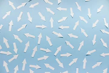 Fotobehang Concept of chaos randomly arranged many white paper arrows on blue background. © dariaren
