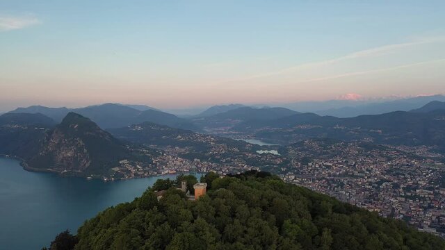 Aerial footage of the sunset over the Monte Bre overlooking the city and lake of Lugano in Canton Ticino in Switzerland. Shot with a forward and revealing motion