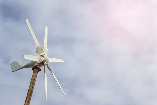 Small windmill wind turbine with blades on the background of sky.