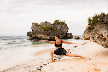 Bali beach yoga. Caucasian woman practicing Virabhadrasana II, Warrior II Pose. Strong body....