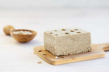 Halva with sunflower seeds on a wooden board.