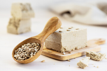 Sunflower seeds in a wooden spoon with halva on the table.