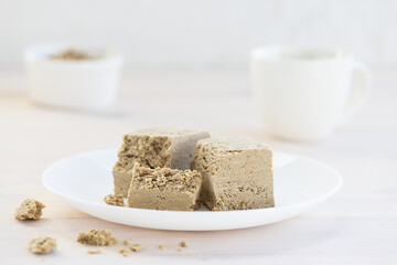Halva pieces on a white plate with a cup of tea.