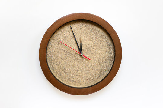 Concept of time - clock filled with real sand with arrows showing five minutes to twelve on white background.