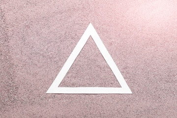 Simple concept white paper triangle on pink real sand background.