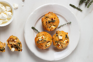Spinach Feta cheese breakfast muffins on a plate. White marble background.