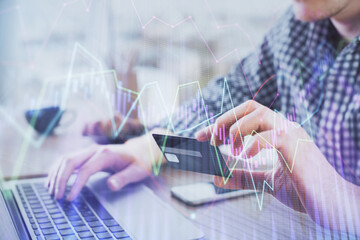 Double exposure of man hands holding a credit card and Forex graph drawing. Stock trading and digital fintech in Internet E-commerce concept.