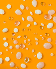 Orange abstract background with beads. Cabochons made of rock crystal and rose quartz.Flat lay.