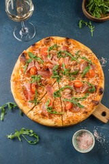 Pizza with prosciutto, arugula and tomatoes