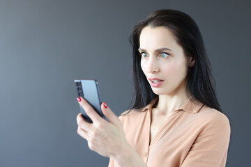 Portrait of surprised woman looking at smartphone