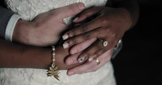 Close up of a interracial couple hands as they cuddle for the photographer at night.