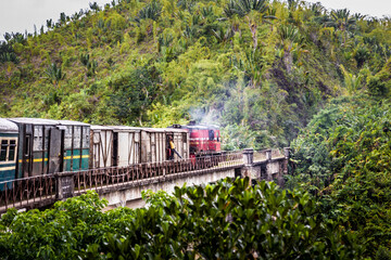 An Old train in Madagascar going through the jungle from Fianarantsoa to Manakara, A man gets to...