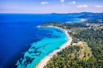 Fototapeta na wymiar Beautiful Beach With Golden Sand And Clear Water. Turquoise coast with blue water and golden sand in Europe. Summer vacation background with turquoise sea water bay and pine trees aerial drone photo