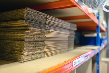 Fototapeta premium A selection of flat shipping boxes/cartons on a shelf ready to be made up and packed with product. Warehouse, despatch, shipping, parcel concept