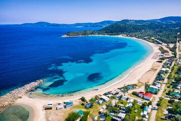 Beautiful Beach With Golden Sand And Clear Water. Turquoise coast with blue water and golden sand in Europe. Summer vacation background with turquoise sea water bay and pine trees aerial drone photo