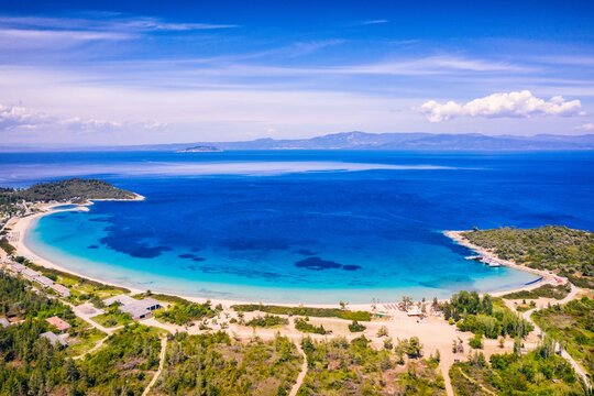 Beautiful Beach With Golden Sand And Clear Water. Turquoise coast with blue water and golden sand in Europe. Summer vacation background with turquoise sea water bay and pine trees aerial drone photo