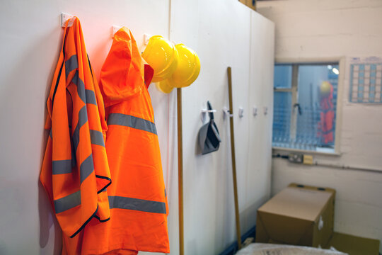 High Visibility Protective Clothing And Hard Hats Hanging Up In A Warehouse For Easy Access For The Workers. Warehouse, Stores, Safety Gear Concept