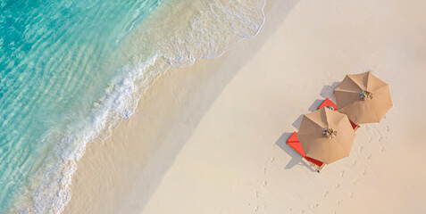 Aerial view of amazing beach with umbrellas and lounge chairs beds close to turquoise sea. Top view...