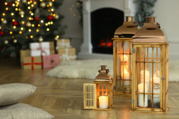 Fototapeta na wymiar Christmas lanterns with burning candles in decorated living room. Space for text