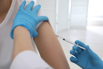 Doctor giving injection to woman in hospital, closeup. Immunization concept