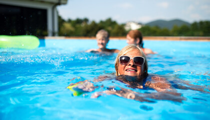 Portrait of senior woman in swimming pool outdoors in backyard.