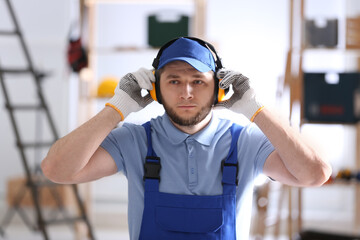 Worker wearing safety headphones indoors. Hearing protection device