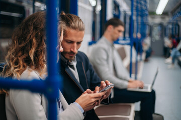 young couple discussing online news in a subway car .