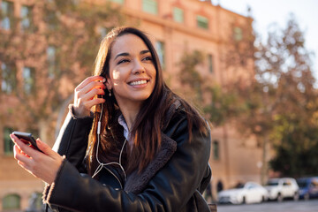 joyful woman putting on the earphones of her phone