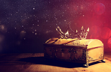 low key image of beautiful queen or king crown over gold treasure chest. vintage filtered. fantasy medieval period