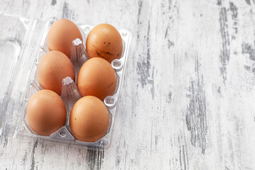 Close-up view of raw chicken eggs in egg box on white wooden background	