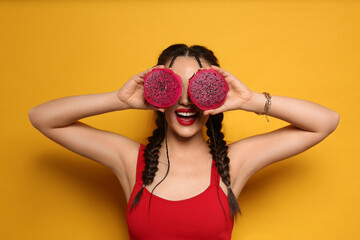 Young woman with fresh pitahaya on yellow background. Exotic fruit
