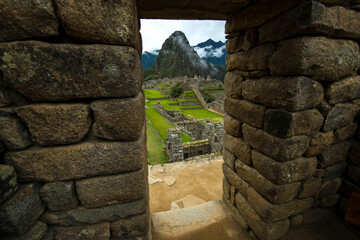 view of Machu Picchu in mystic fog  through opening in ancient wall 