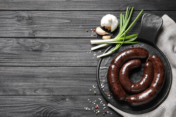 Tasty blood sausages served on black wooden table, flat lay. Space for text