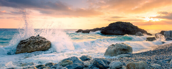 Sea waves break on big stone with beautiful white splashes, sunrise. Panorama