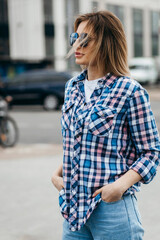 Fashion portrait of beautiful woman with beautiful face, wearing grunge plaid shirt. Posing alone.