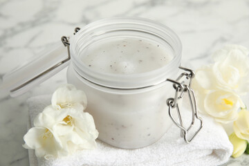 Obraz na płótnie Canvas Jar of salt scrub, freesia flowers and towel on white marble table