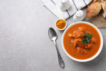 Bowl of delicious chicken curry on light grey table, flat lay. Space for text