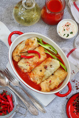 Russian stuffed cabbage rolls served with tomatoes, dill and sour cream in heat-resistant black dishes on a serving board