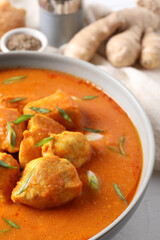 Bowl of delicious chicken curry on white table, closeup