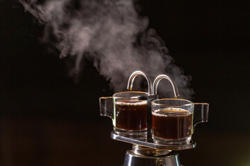 Heat vapor emitted from the coffee machine..Two black coffeemakers in a black background. hot coffee and the heat vapor is gushed out from the coffee percolator tube..