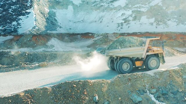 Mining industry concept. Side view of a loaded truck riding along the mine site