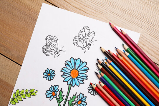 Child's colored drawing with pencils on wooden table, flat lay