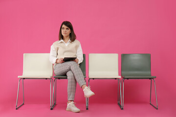 Fototapeta na wymiar Young woman with tablet waiting for job interview on pink background