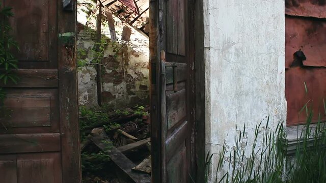 The old door of an abandoned and ruined house. An old door in an abandoned building closes on its own.