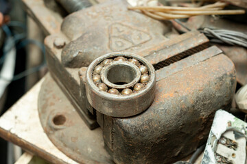 The bearing, rusty and covered in oil, rests on a large vise.